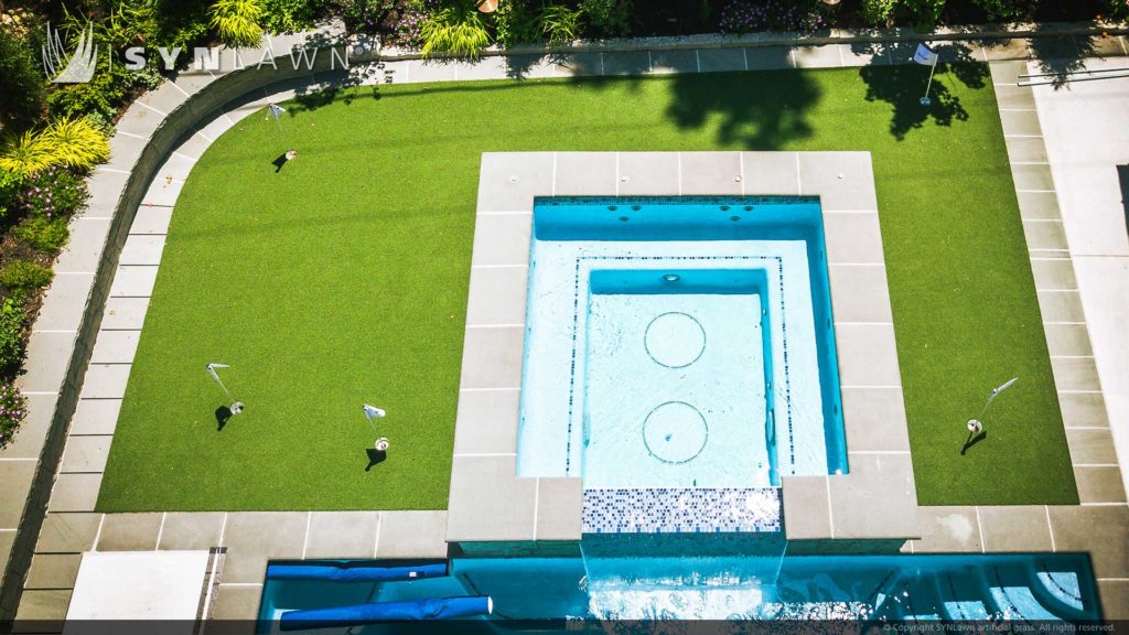 Artificial grass backyard with a pool